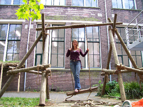 Kunstenares Marjolein van Heest, staand op haar kunstwerk 'Schommelend', met op de achtergrond de tekst in Morse-code
